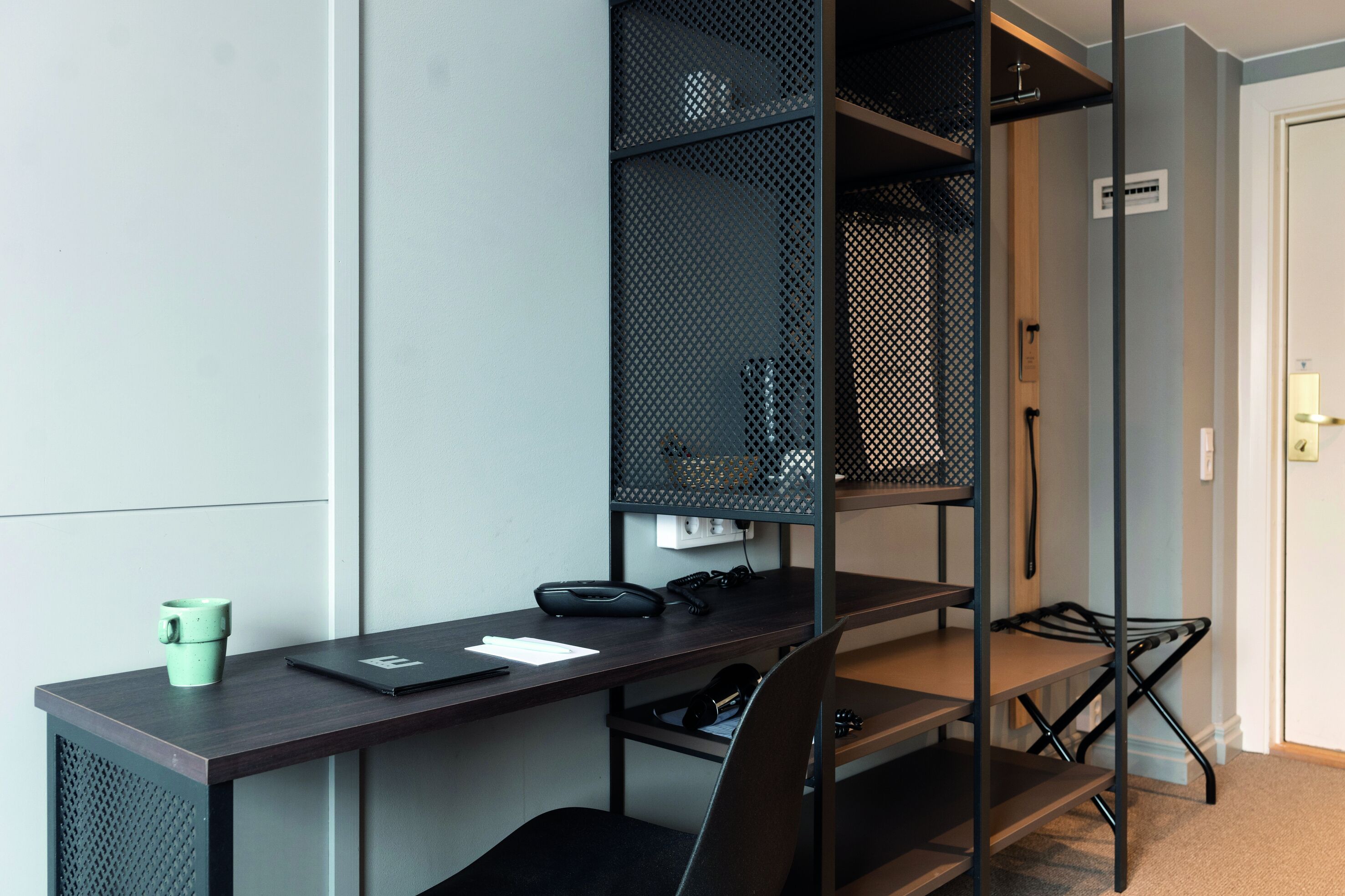 A compact workspace with a desk, chair, and shelving unit.