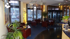 Un vestíbulo de hotel con zonas de estar, ventanas amplias y una recepción.