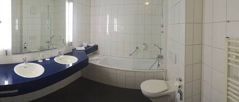 A bathroom with two sinks, a bathtub, and a toilet.