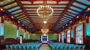 Ein großer Saal mit Reihen von Stühlen und einer zentralen Bühne, vermutlich für Veranstaltungen oder Konferenzen genutzt.