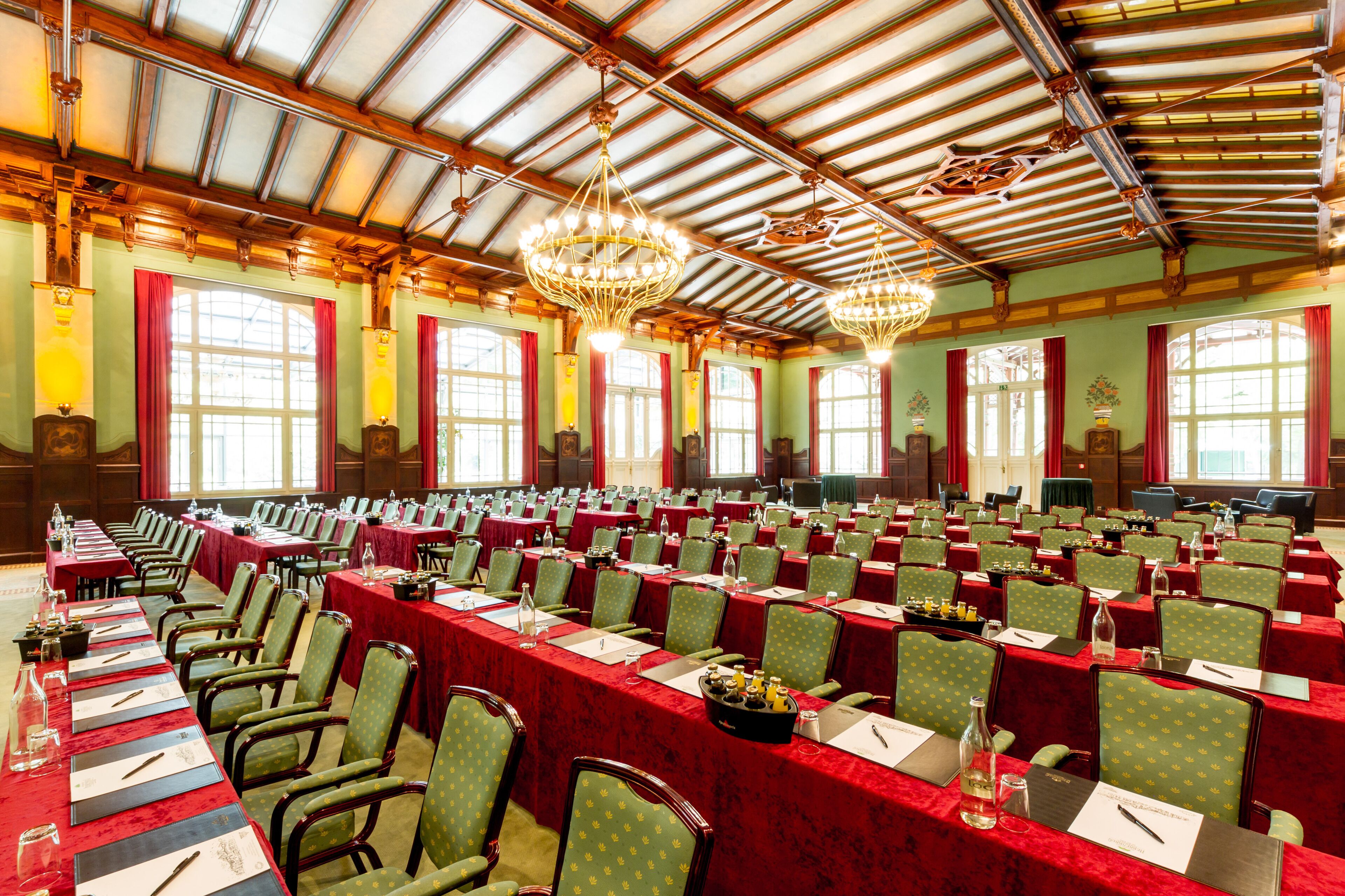 A large conference room with rows of tables and chairs, equipped with nameplates and water bottles.