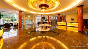 Un hall espacioso con una mesa redonda central, una recepción y un gran elemento decorativo circular en el techo.