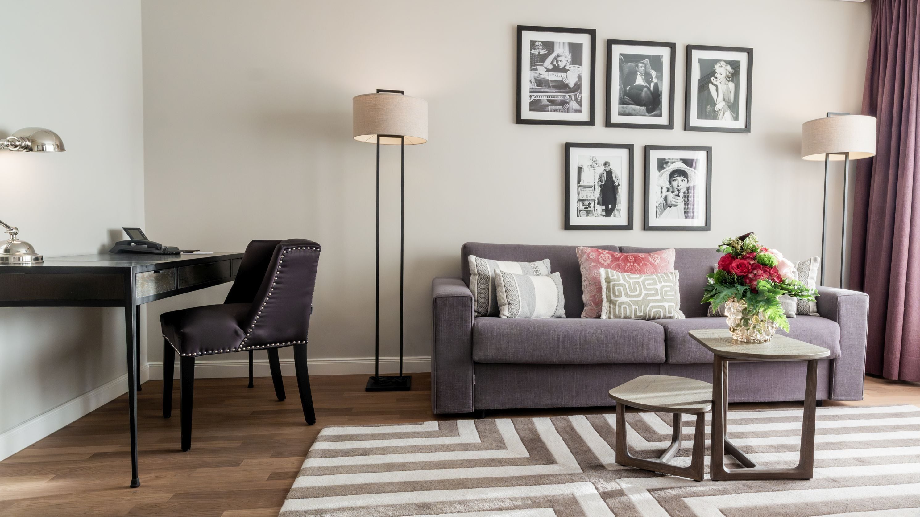 Un salon moderne avec un canapé gris, un fauteuil noir, une petite table ronde et un lampadaire.