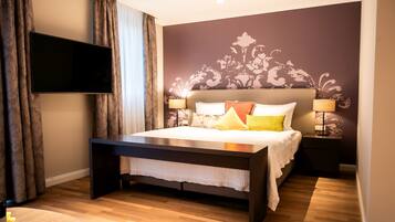 Un dormitorio con cama, mesitas de noche, televisor y una pared con estampado floral.