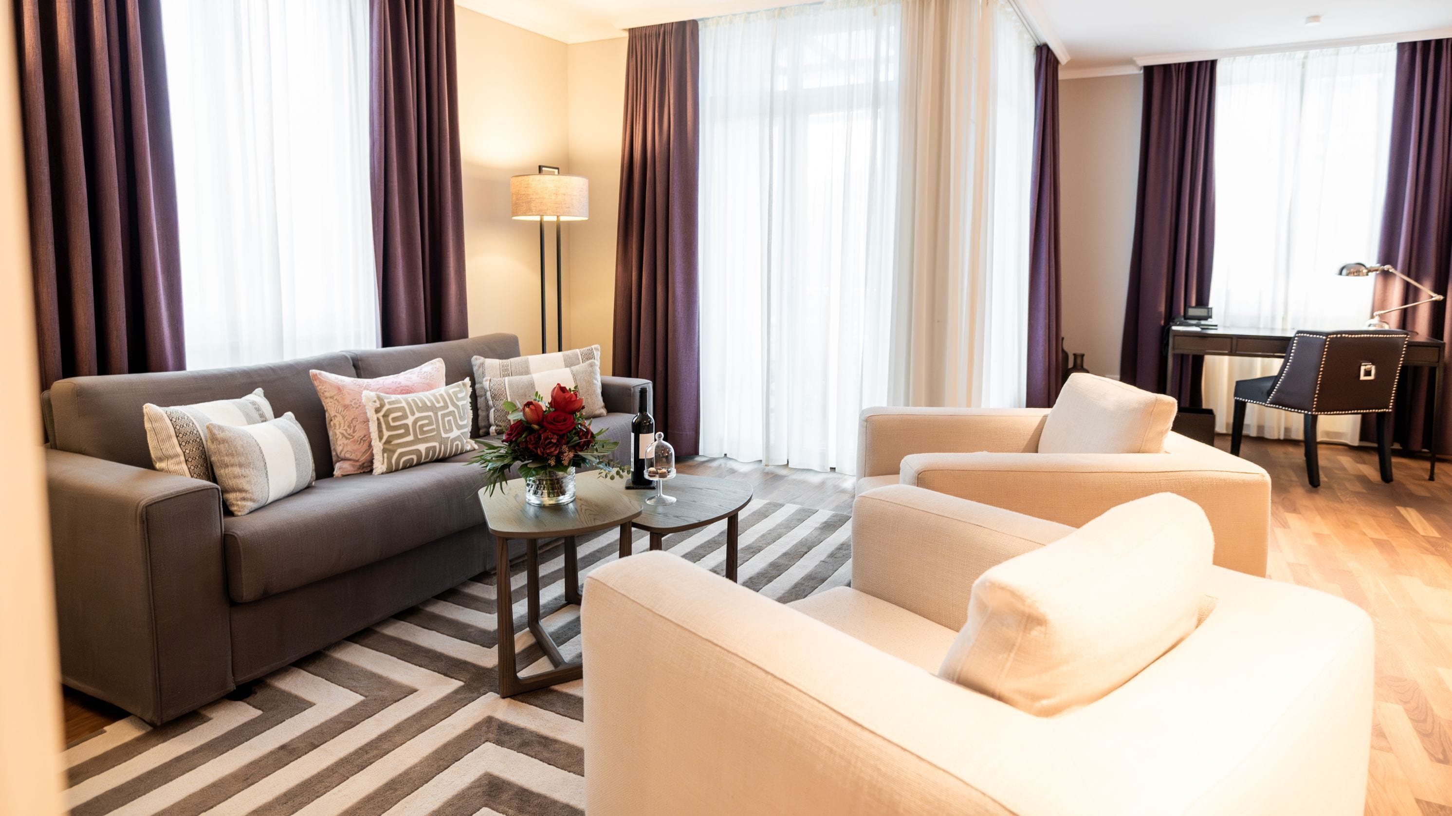 Ein modernes Wohnzimmer mit Sofa, Sesseln, einem Couchtisch und einem Schreibtisch.