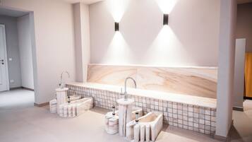 A modern bathroom with a large bathtub, two sinks, and a marble backsplash.