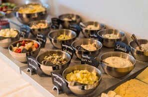 A buffet with various dishes labeled in German, including 'Lachsquollen' and 'Schwäbisch'. - SOLTHUS Hotel & SPA (Ostseebad Baabe)