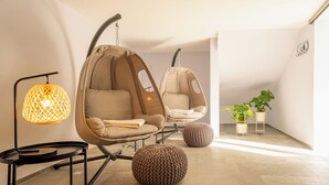 Um interior moderno com duas cadeiras suspensas, uma luminária de chão e plantas em vasos.