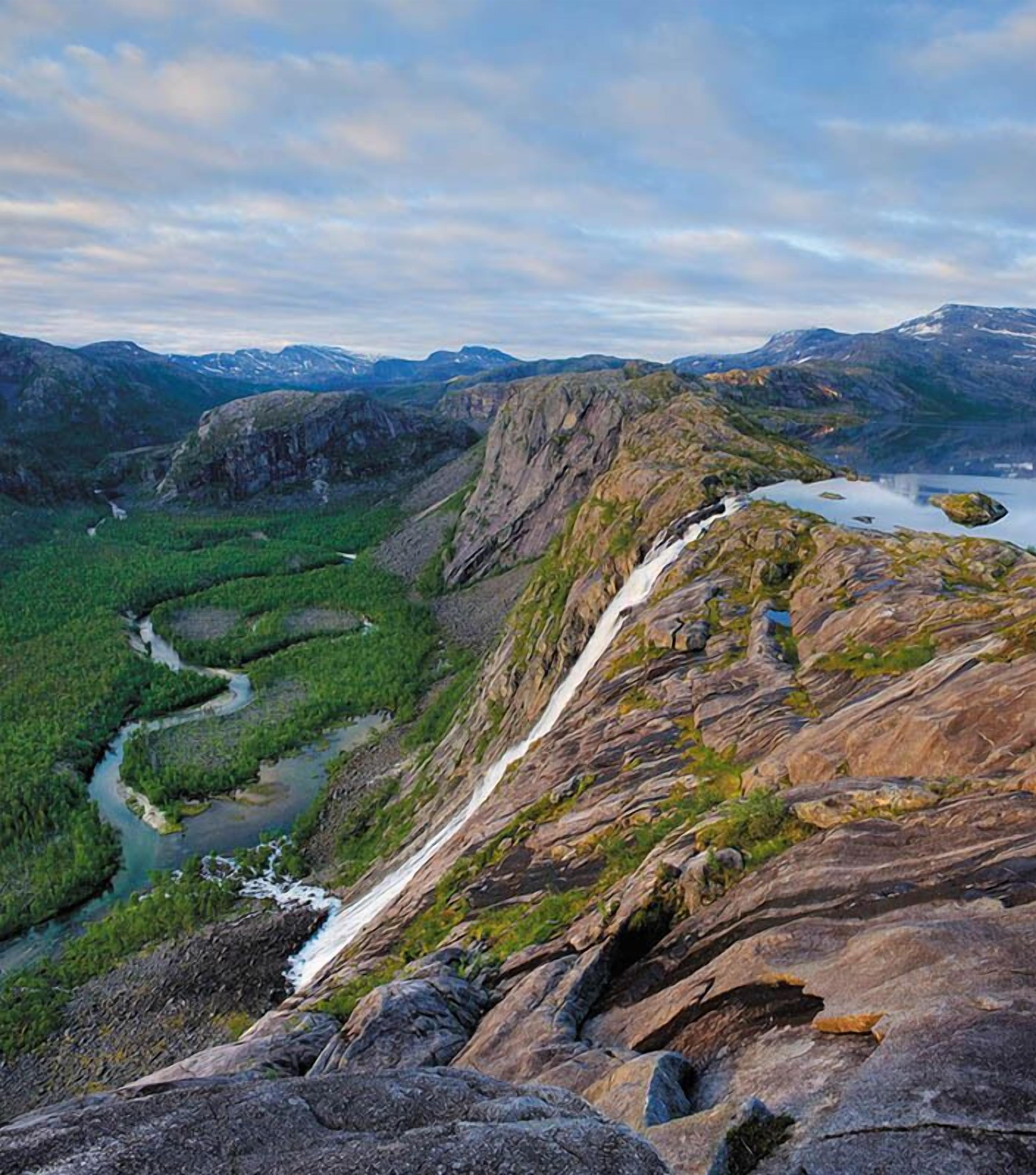 Un paisaje montañoso con un río, una cascada y un lago.
