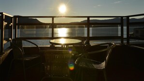A balcony with a table and chairs overlooking a body of water and distant mountains during sunset. - Scandic Fauske Hotel (Fauske)