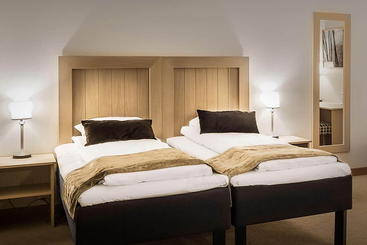 A double bed with a wooden headboard, two bedside tables with lamps, and a mirror on the wall.