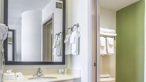 Bany d'hotel amb un lavabo, un mirall i un vàter blancs.