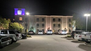 Un pàrquing amb diversos vehicles, incloent SUV i furgonetes, davant d'un edifici amb el rètol Sleep Inn.