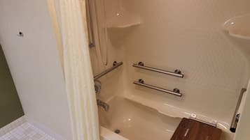 A bathroom with a bathtub, grab bars, and a wooden tray.