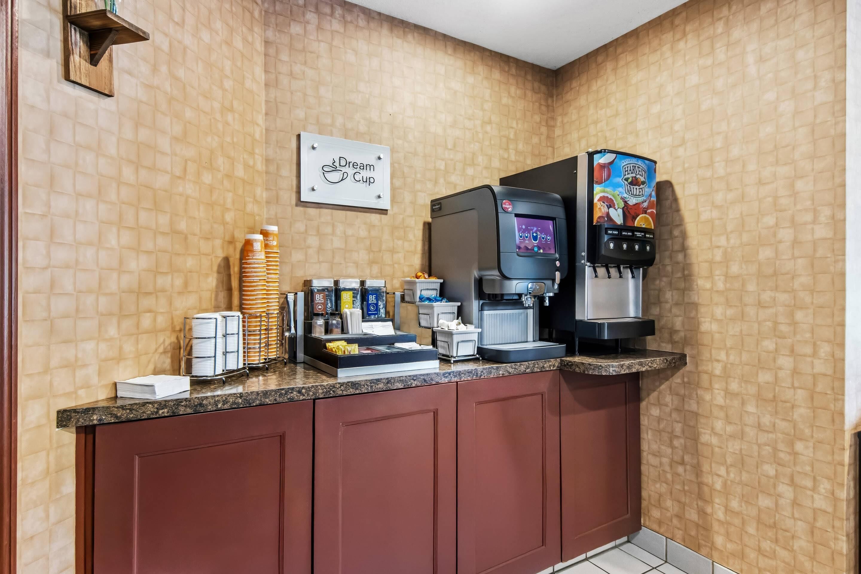 A coffee station with a coffee machine, a beverage dispenser, and a sign that reads 'Dream Cup.'