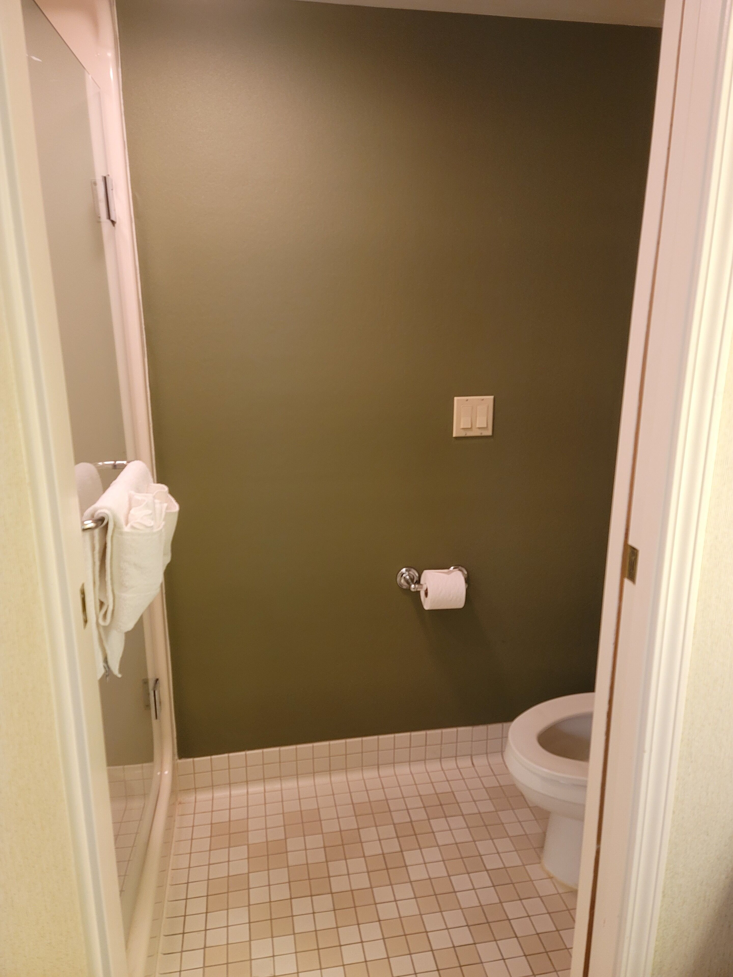 Une salle de bain équipée de toilettes, d’un porte-serviettes et d’un distributeur d’essuie-tout.