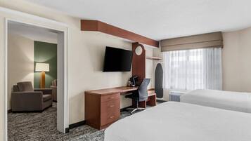 Een hotelkamer met een bed, een bureau met stoel, een televisie en een raam met gordijnen.