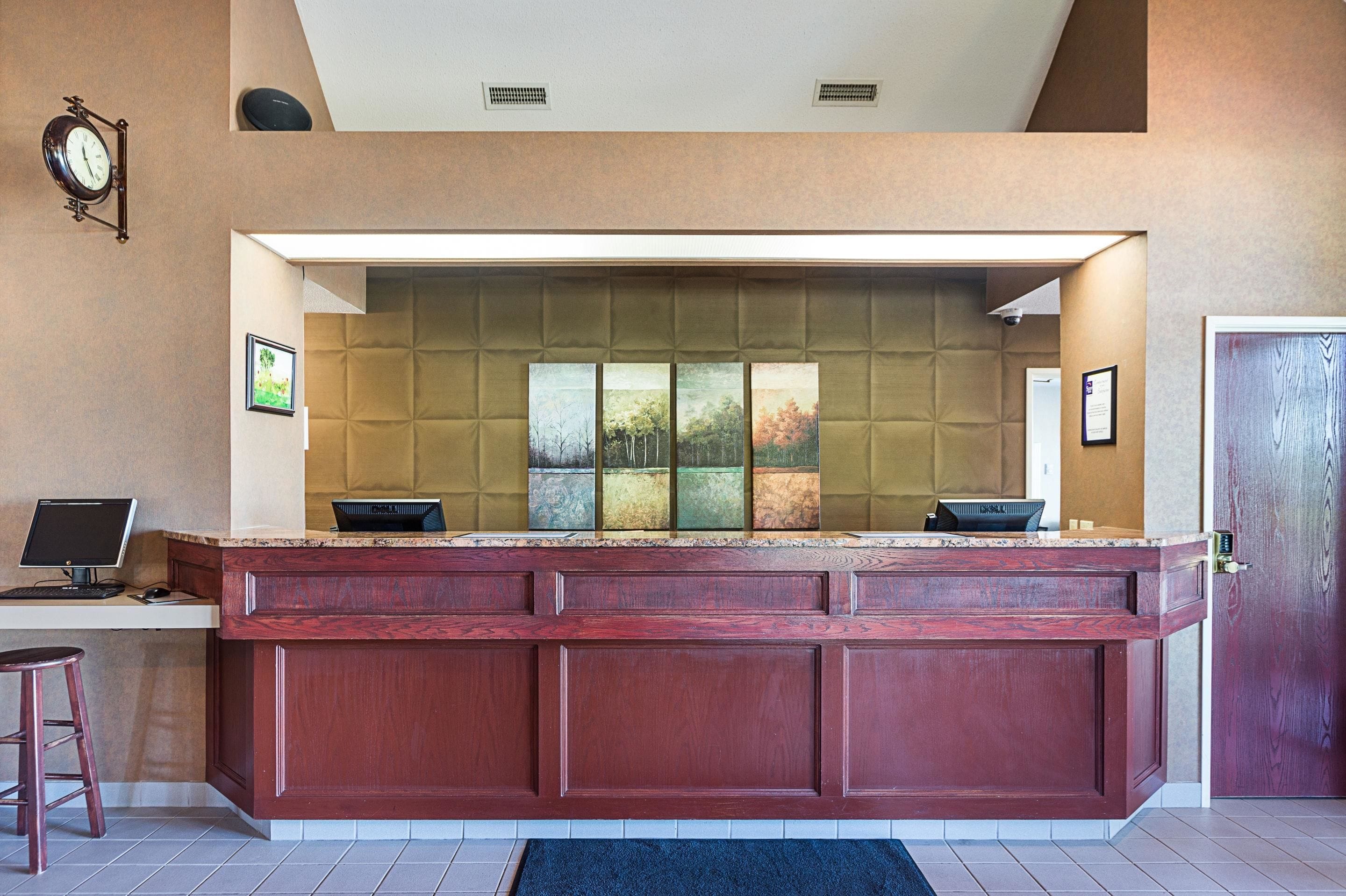 A reception desk with a computer, a clock, and framed pictures on the wall.
