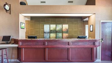 A reception desk with a computer, a clock, and framed pictures on the wall.