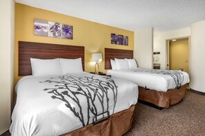 A hotel room with two beds, a wooden headboard, a lamp, and a wall with floral artwork.