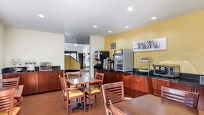 A modern kitchen with wooden cabinets, a coffee station, and a microwave.
