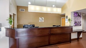 A reception desk with a sign reading "Sleep Inn" and a welcome mat with "Welcome. Henderson" text.