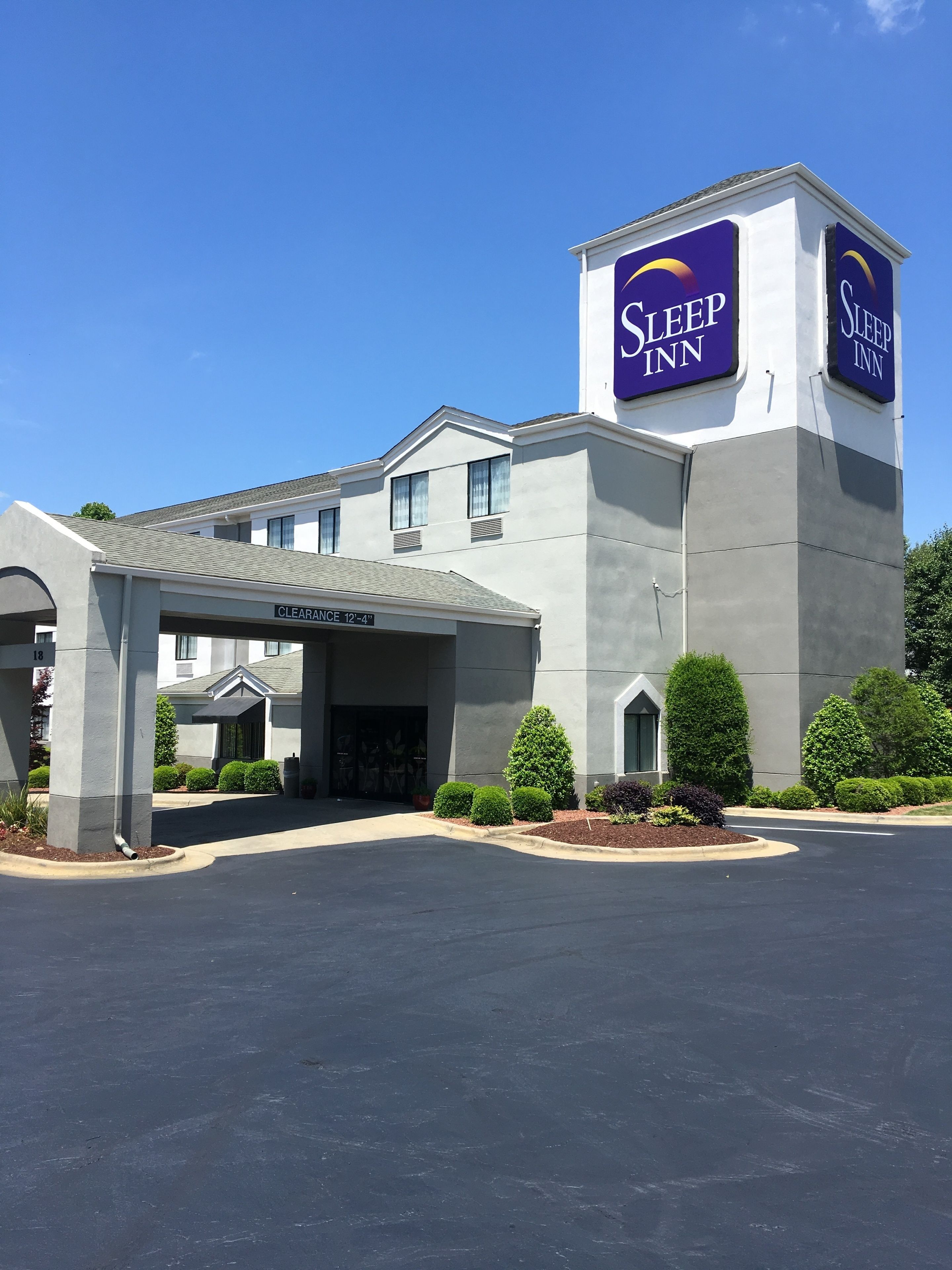 Un hôtel Sleep Inn doté d’une entrée bien visible, d’un espace de stationnement couvert et d’un panneau indiquant une hauteur libre de 12 pieds et 4 pouces.