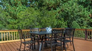 A deck with a table and chairs, surrounded by dense green foliage.