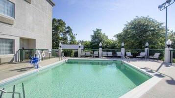 Relax by the pool surrounded by comfortable lounge chairs and a shaded seating area.