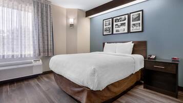 Een hotelkamer met een bed, nachtkastje, een aan de muur bevestigd telefoon en ingelijste foto's.