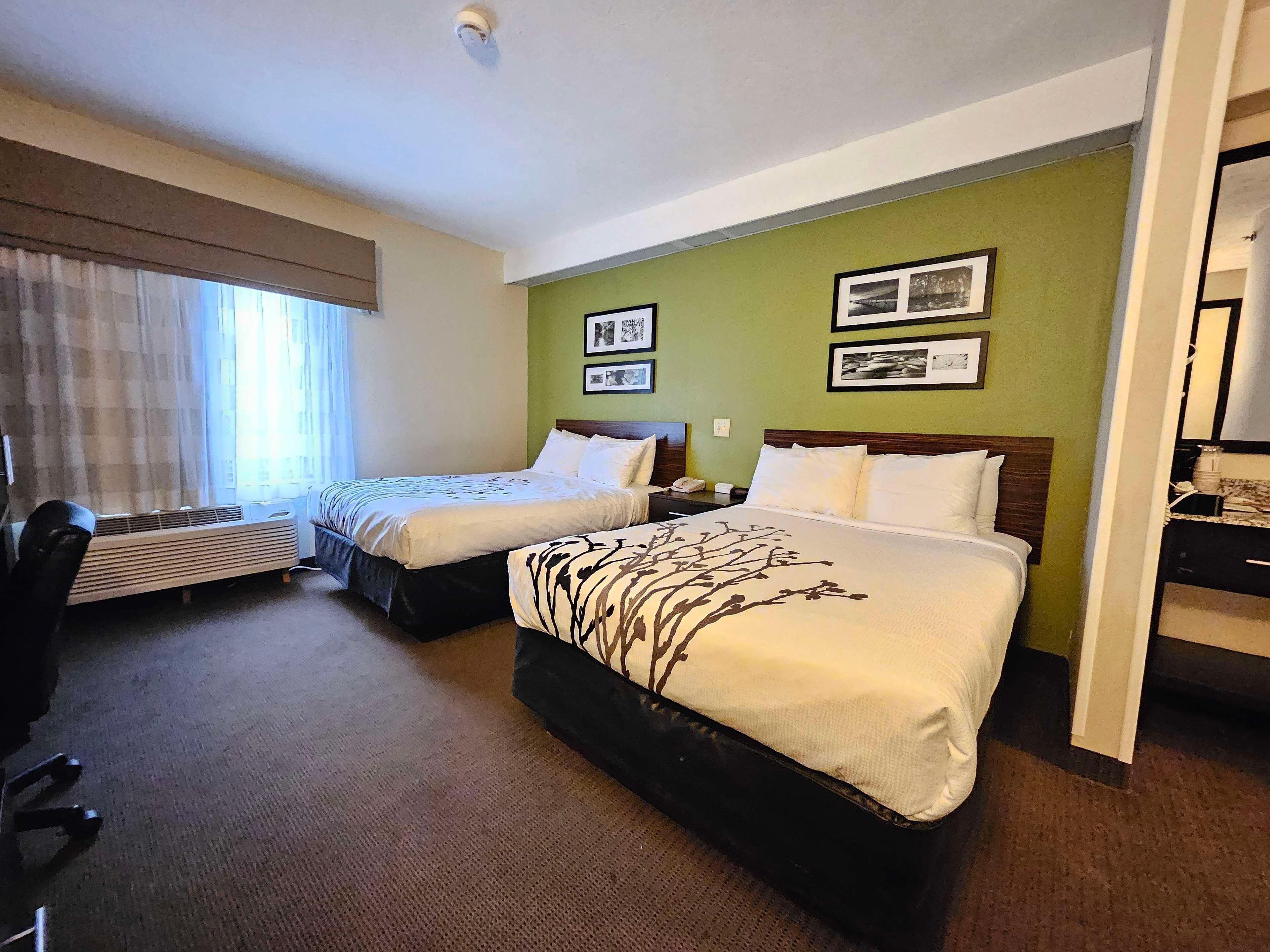 A hotel room with two beds, a desk, a chair, and a radiator.