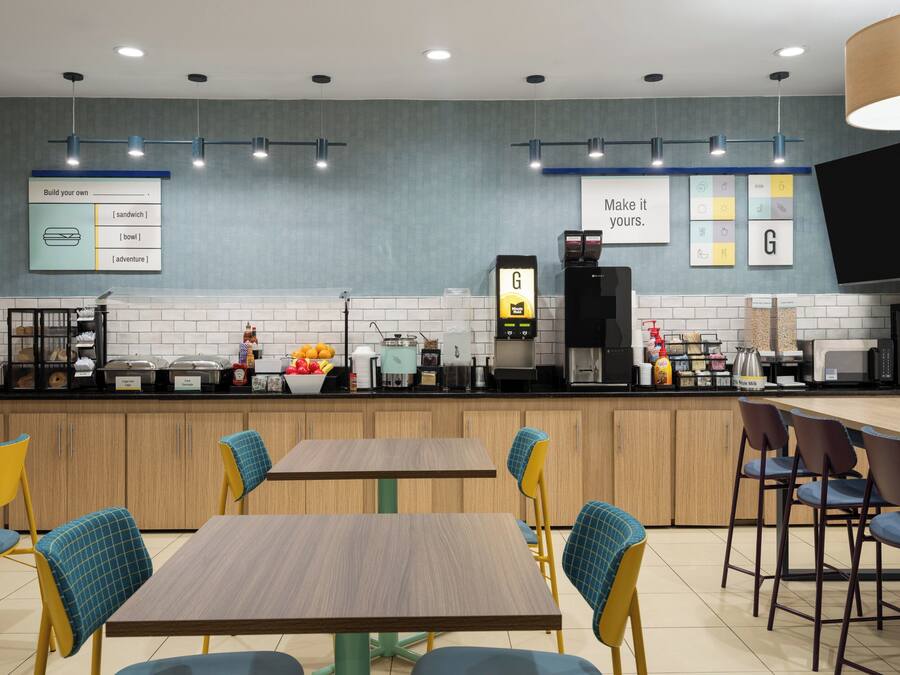 Ein modernes Café mit Selbstbedienungsbereich, Sitzgelegenheiten und einer Speisekarte.