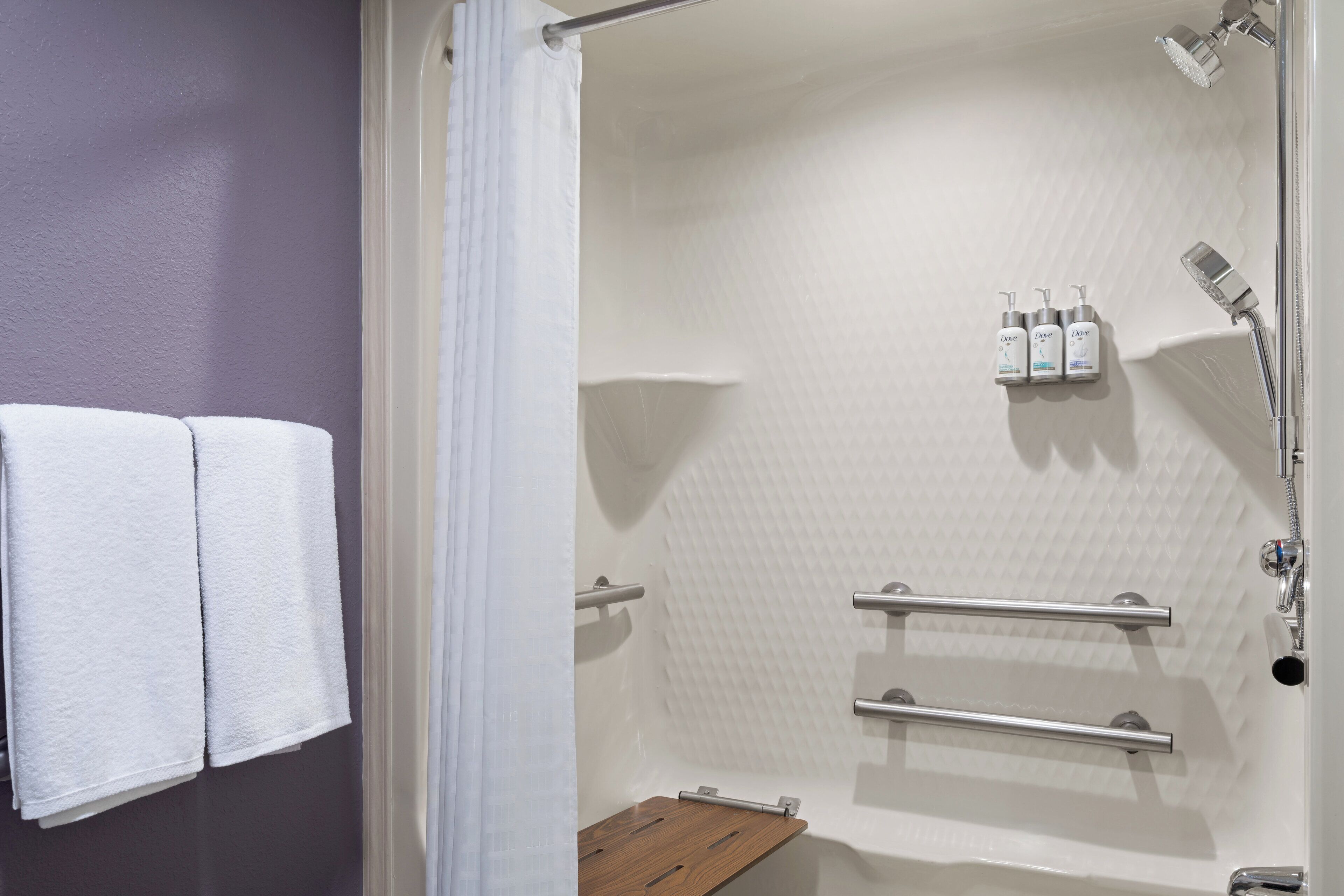 Een moderne douche met een witte, geruite wand, een houten bankje en twee handdoekrekken.