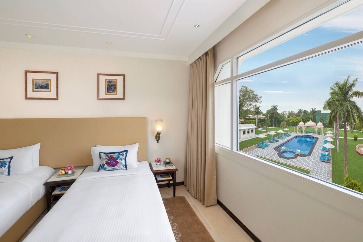 A hotel room with two beds, a view of a pool, and a balcony.