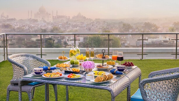 A balcony with a table set for breakfast overlooking a cityscape with a prominent building in the distance. - Tajview,Agra-IHCL SeleQtions (Agra)