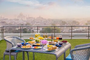 A balcony with a table set for breakfast overlooking a cityscape with a prominent building in the distance. - Tajview,Agra-IHCL SeleQtions (Agra)