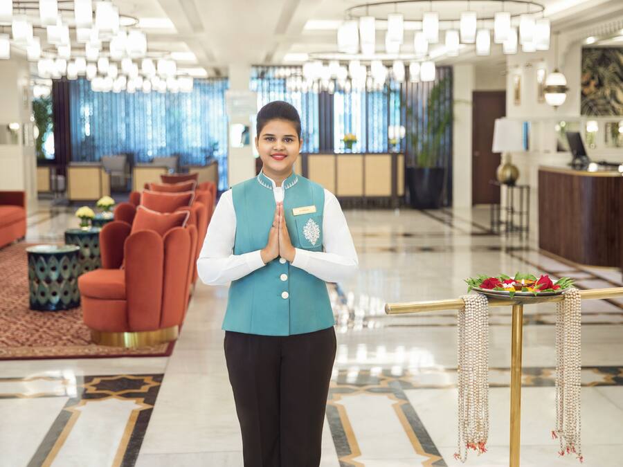 Een hotel lobby met een receptiebalie, een zithoek en moderne kroonluchters.