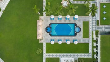 Vista aérea de una zona de piscina con una pileta rectangular, tumbonas y una pequeña fuente circular.