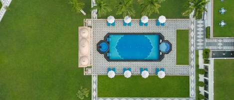 An aerial view of a pool area with a rectangular pool, sun loungers, and a small circular fountain.
