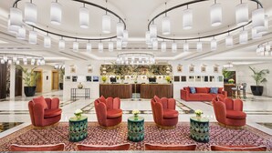 A spacious lobby with a central reception desk, red upholstered chairs, and a patterned carpet. - Tajview,Agra-IHCL SeleQtions (Agra)