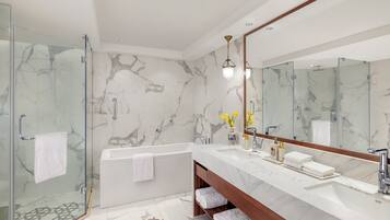 A modern bathroom with a glass-enclosed shower, a marble-tiled floor, a large mirror, and a wooden vanity.