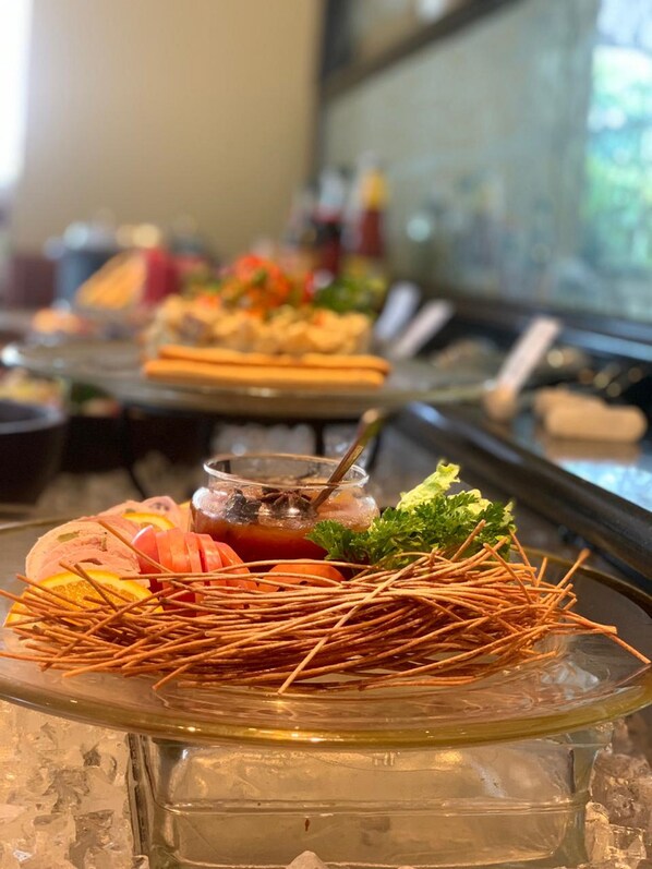 Una mesa de buffet con diversos platos, incluyendo un plato de mariscos con camarones y vegetales, y un vaso de bebida helada con una guarnición.