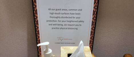 Zona de recepción de hotel con un letrero que dice "TAJVIEW" y un mensaje sobre la desinfección de las áreas para huéspedes y el distanciamiento físico.