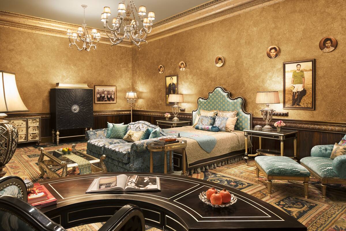 A luxurious bedroom with a large bed, two side tables, a chandelier, and a classic chandelier.