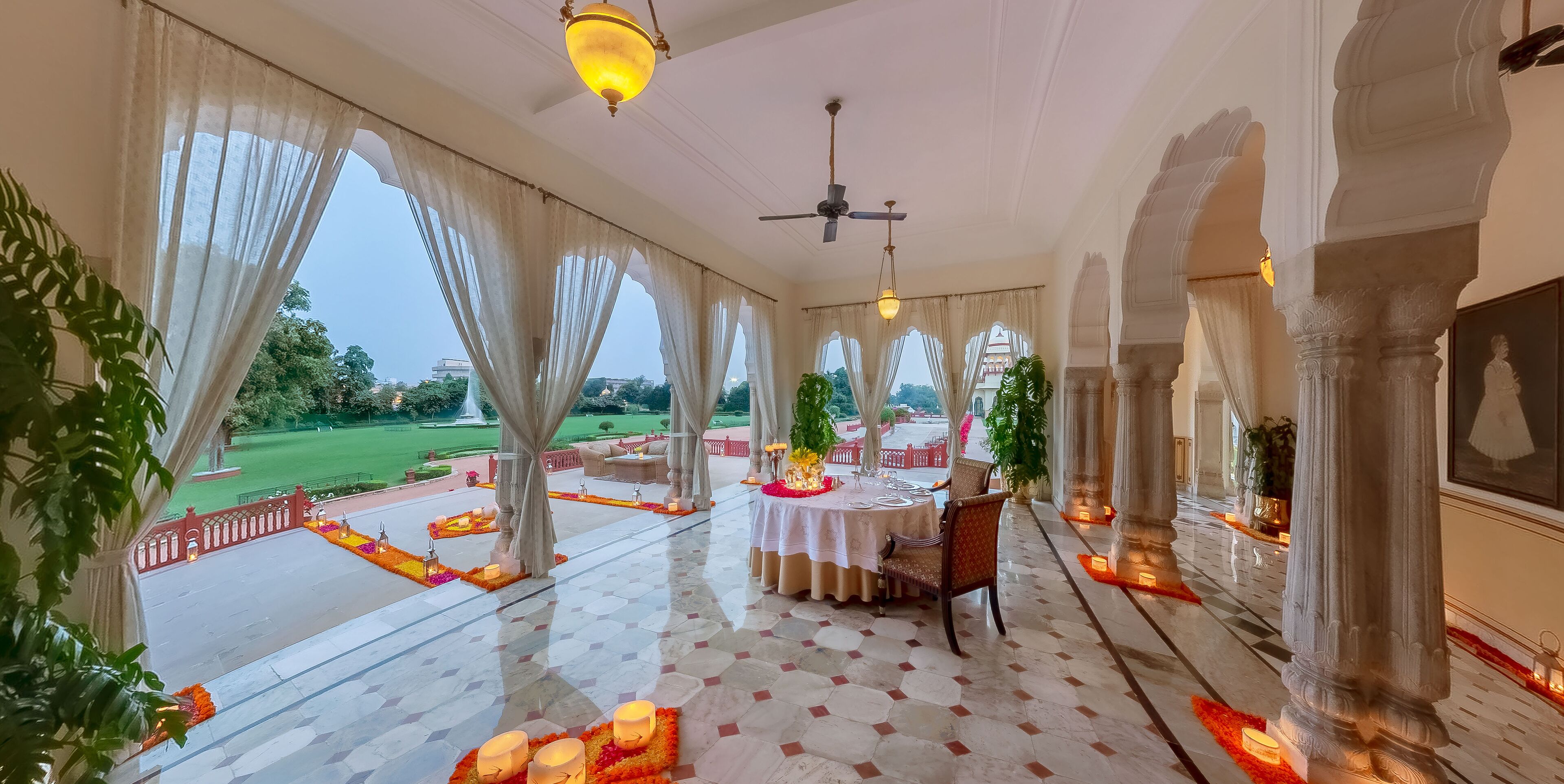 A spacious indoor area with a dining setup, large windows, and a view of a garden.