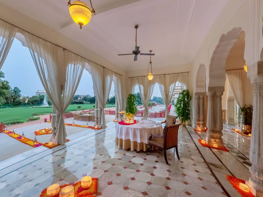 A spacious indoor area with a dining setup, large windows, and a view of a garden.