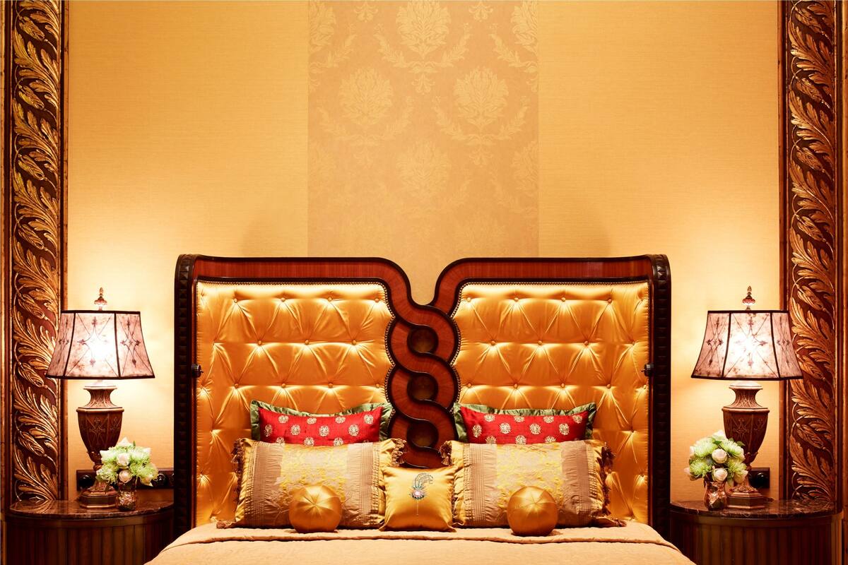 A luxurious bed with a tufted headboard, two bedside lamps, and decorative pillows.