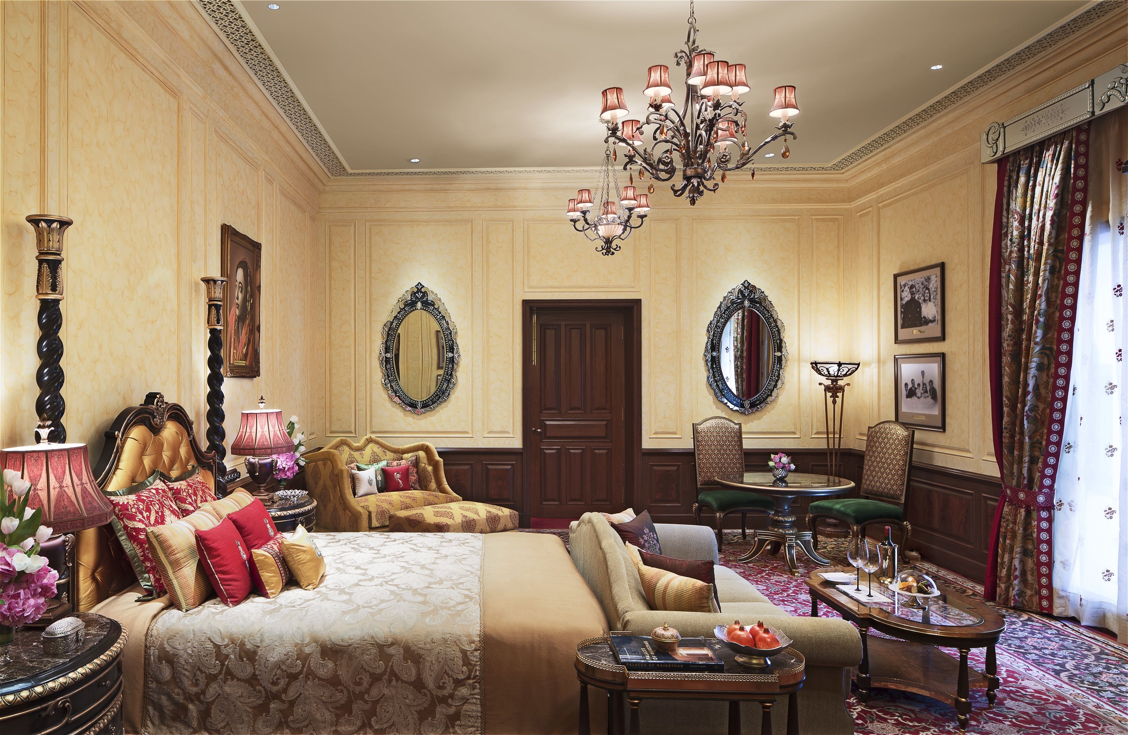 A luxurious bedroom with a large bed, a sitting area, and a dining table.