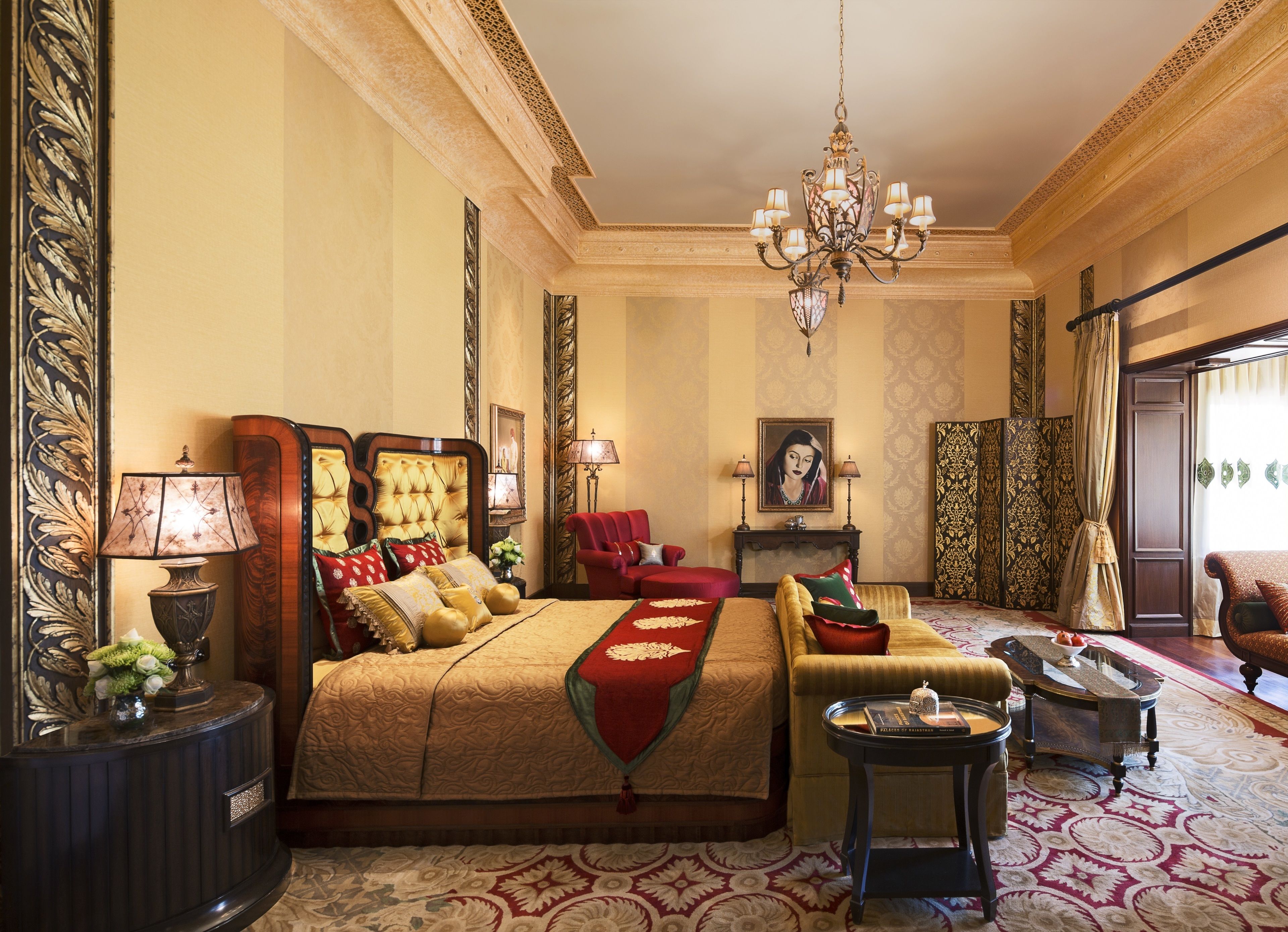 A luxurious bedroom with a large bed, a sitting area, a piano, and a chandelier.