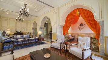 A spacious lobby with a grand chandelier, a sofa set, a coffee table, and an ornate archway.